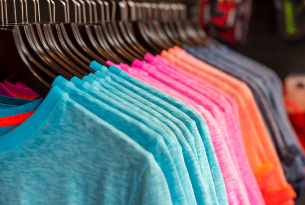 row of colored t-shirts in a store - merchandise multi colored arrangement blue imagens e fotografias de stock