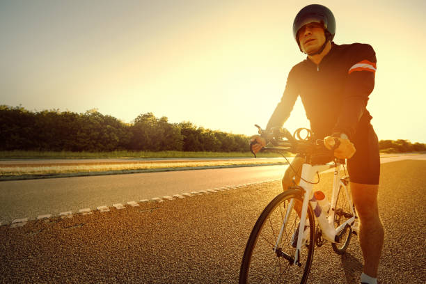 istock Sun rises behind man ready to ride bike 682265328