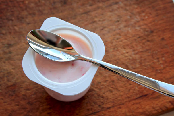 rosa yogurt en vaso de plástico sobre fondo con cuchara de madera. - yogurt yogurt container strawberry spoon fotografías e imágenes de stock