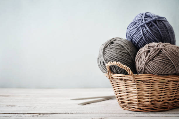 Wool yarn in coils Wool yarn in coils with knitting needles in wicker basket on light blue background clew bay stock pictures, royalty-free photos & images