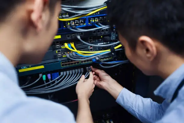 Photo of Young IT engineer inspecting network cable
