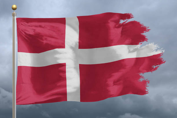 Flag of Denmark tattered and torn with stormy sky