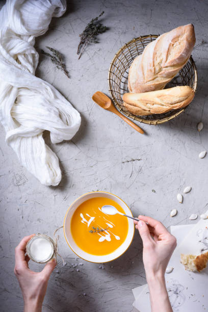 istock A person pouring sour cream in a yellow soup on table. 682298810