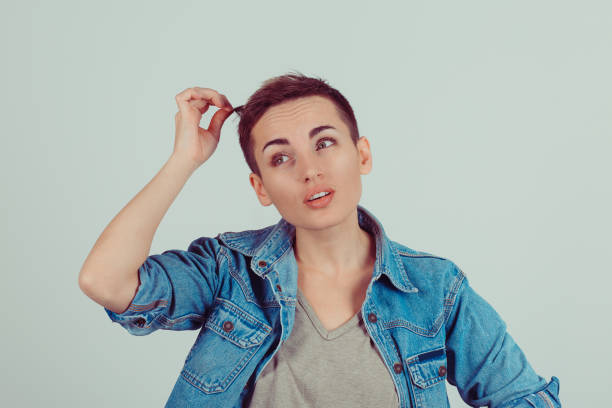 istock Woman pulling her short hair trying to see thinking how much it is grown isolated green grey background wall 682305596