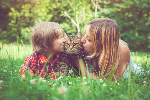 Woman and her son with their cat outdoors in summer
