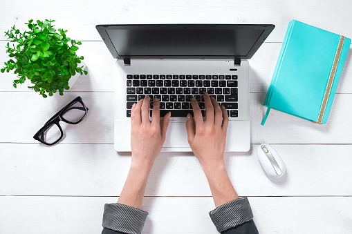 Overhead view of businesswoman working at computer in office. Female workplace.