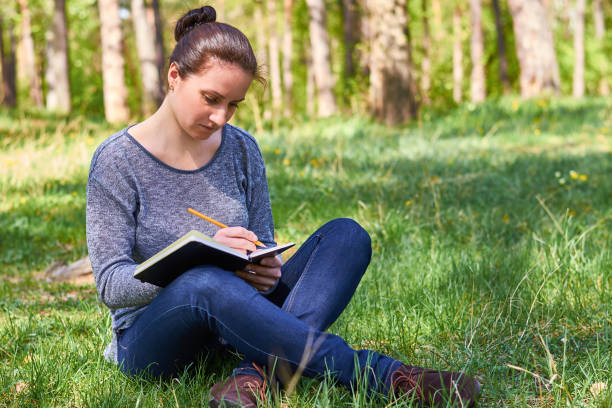 istock beautiful young girl in nature, making notes in a notebook 682332666