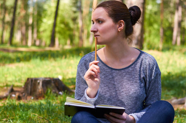 istock beautiful young girl in nature, making notes in a notebook 682332672