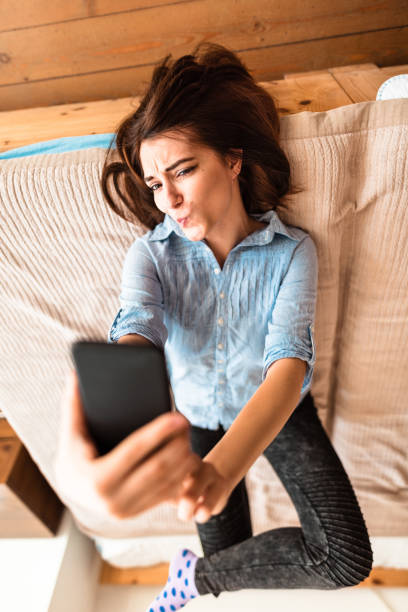 adolescente fare un selfie sul letto - one teenage girl only on the phone bed lying on front foto e immagini stock