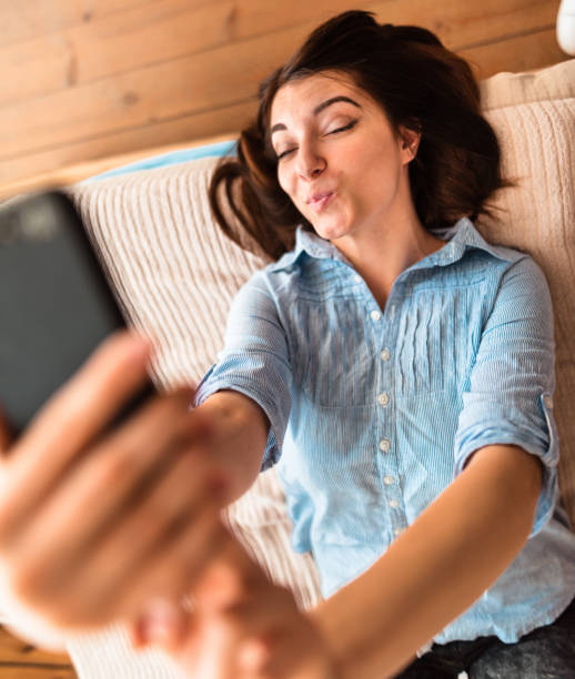 adolescente levar uma selfie na cama - one teenage girl only on the phone bed lying on front - fotografias e filmes do acervo