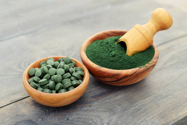 Spirulina Ground spirulina and spirulina in pills over black wooden background chlorella stock pictures, royalty-free photos & images