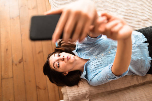 adolescente fare un selfie sul letto - one teenage girl only on the phone bed lying on front foto e immagini stock