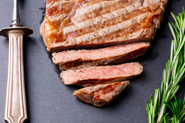 istock Grilled sliced beef steak on slate stone table. Top view. 682346852