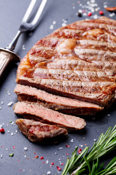 istock Grilled sliced beef steak on slate stone table. Top view. 682349312