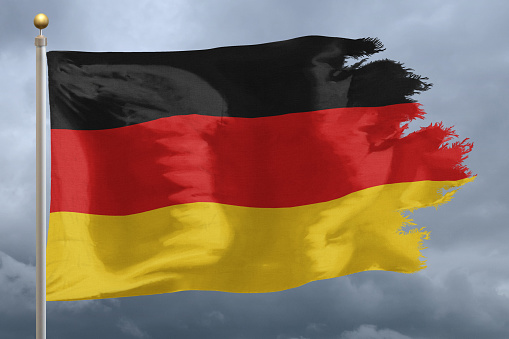 Flag of Germany tattered and torn with stormy sky