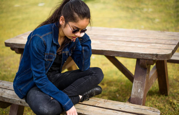 unhappy girl sitting at picnic table - one person child serene people failure imagens e fotografias de stock