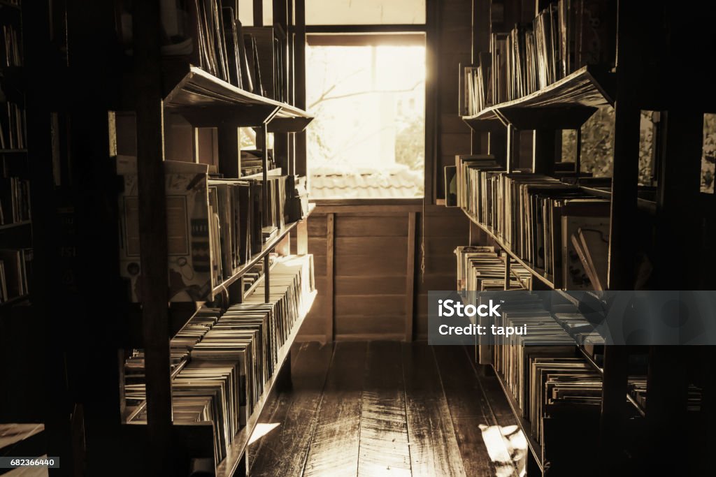 In the old library, the books on the shelves were cluttered, the light shining out of the window in a lonely atmosphere, vintage style. Bookstore Stock Photo