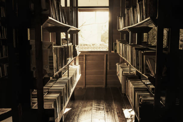 In the old library, the books on the shelves were cluttered, the light shining out of the window in a lonely atmosphere, vintage style. stock photo