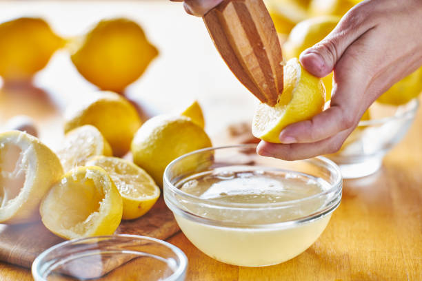 istock squeezing fresh lemon juice with wooden reamer into bowl 682373760