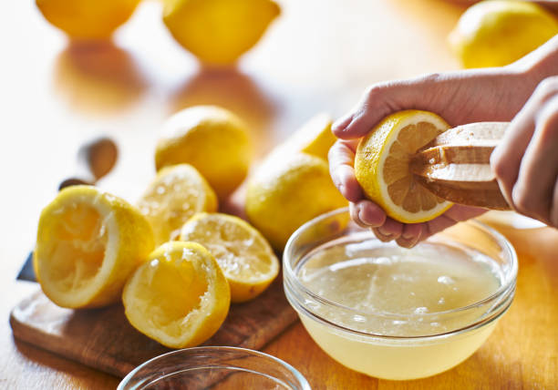 istock squeezing fresh lemon juice with wooden reamer into bowl 682373792