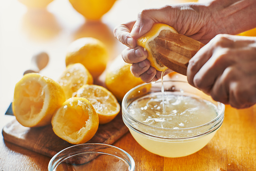 woman's hand squeezing juice from a lemon with wooden tool shot with selective focus