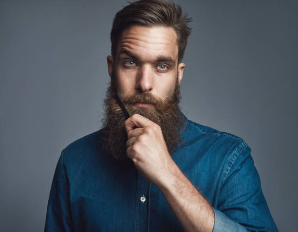 istock Young man holding his beard with blank stare 682380930