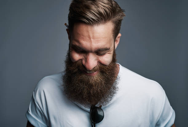 rire le jeune homme à la grande barbe floue - regarder vers le bas photos et images de collection