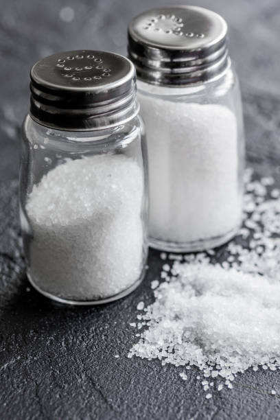 istock salt in glass bottle scattered on dark table background 682385780