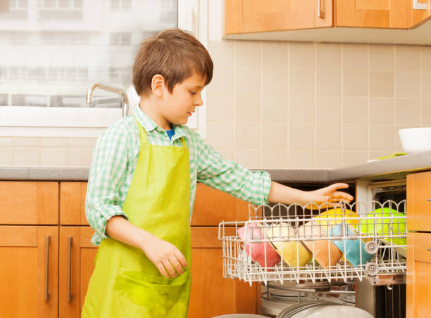 istock Kid boy getting out clean crockery of dishwasher 682394638