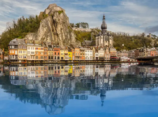 Nice reflection of the village Dinant in Belgium in the river Maas. Church and colorful houses