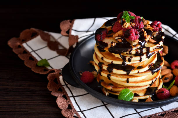 istock Homemade Pancake with raspberries, almonds and chocolate on a black background 682406830