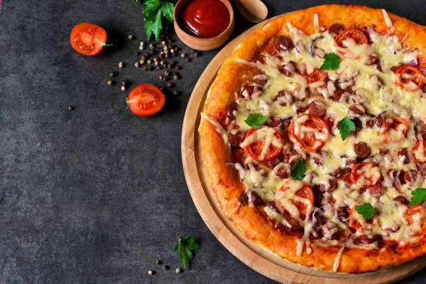 istock Home pizza with salami, tomato and cheese on a black background 682408586