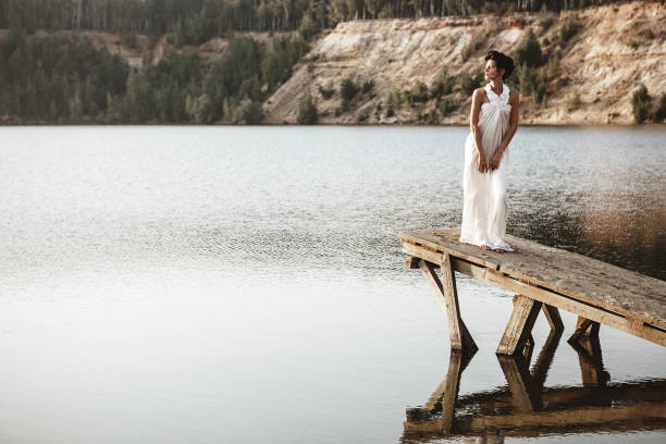istock girl standing on a pier on a lake 682423516