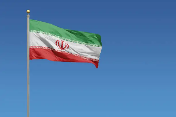 Flag of Iran in front of a clear blue sky