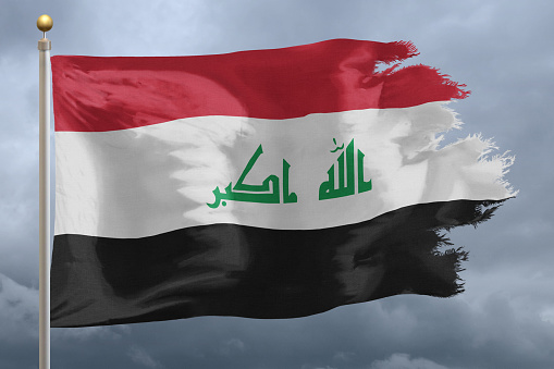 Flag of Iraq tattered and torn with stormy sky