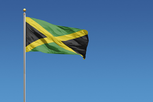 Flag of Jamaica in front of a clear blue sky