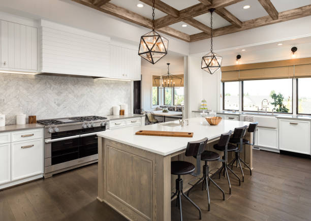 beautiful kitchen in new luxury home with island and pendant light fixtures Kitchen Interior with Island, Sink, Cabinets, and Hardwood Floors in New Luxury Home. Includes elegant pendant light fixtures and wood beam ceiling roof beam stock pictures, royalty-free photos & images