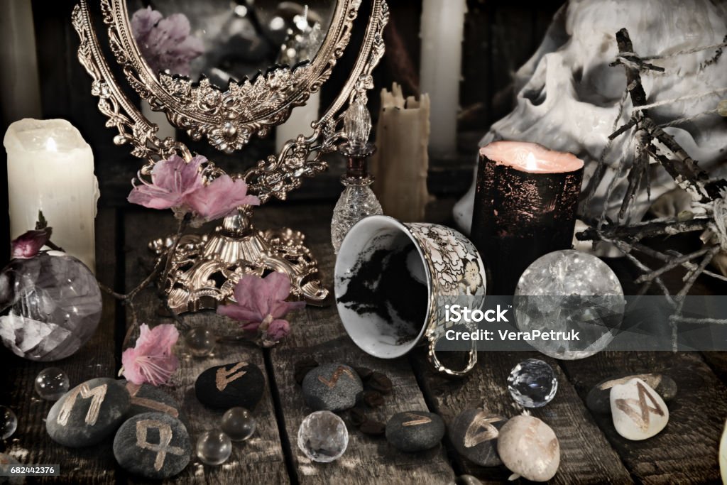 Close up of mystic objects, skull and pink flowers Halloween background, black magic ritual or spell, occult and esoteric objects on witch table Ancient Stock Photo