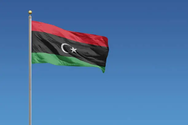 Flag of Libya in front of a clear blue sky