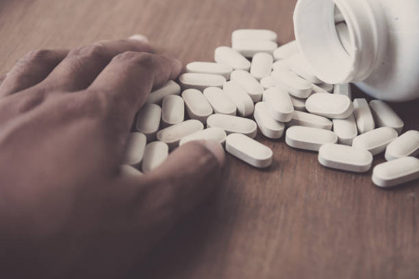istock medicine pill on hand with wood table background 682464462