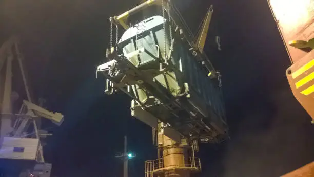 Industrial seaport at night. The rotation of the car with grain using a tower crane.