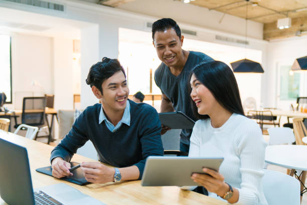 Young design team in an informal meeting Young design team in a modern looking office having an informal meeting and looking at information on a digital tablet. Bangkok, Thailand. April 2017 asia stock pictures, royalty-free photos & images