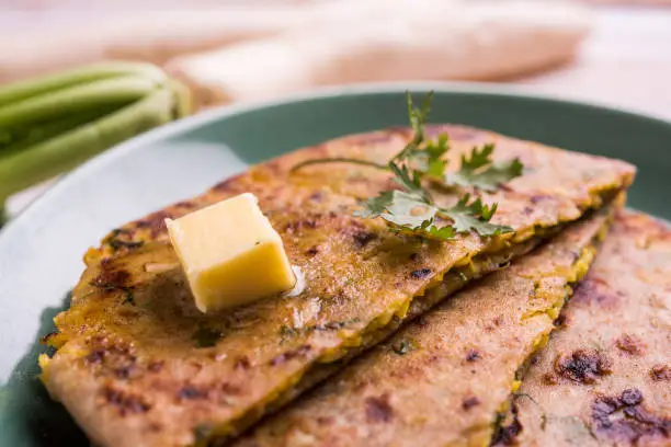 Photo of Daikon, radish, mooli or muli paratha or stuffed radish paratha, indian or pakistani favourite recipe served with butter and tomato ketchup, selective focus