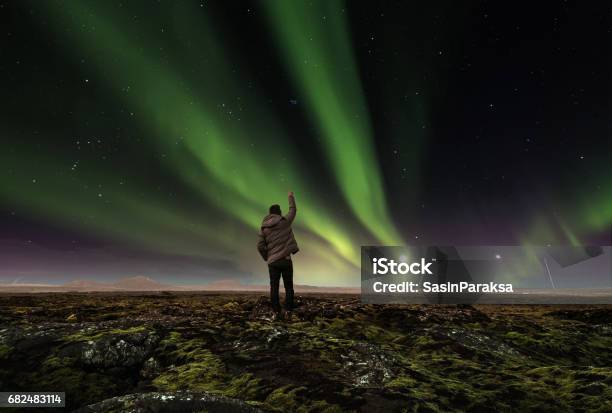 Landscape Of Amazing Beautiful Natural Phenomenon Aurora Borealis With A Man Raising Arm Traveling In Iceland Stock Photo - Download Image Now