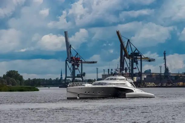 Large silver trimaran. Luxury yacht sailing by the river in Riga