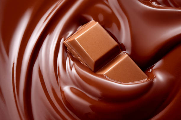 geschmolzene schokolade mit schokoladenstückchen heiße flüssigkeit. hintergrund. - vollmilchschokolade stock-fotos und bilder