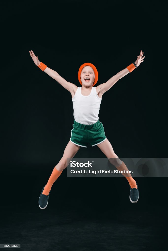 Garçon heureux Sportswear sautant et regardant la caméra isolée sur fond noir - Photo de Enfant libre de droits