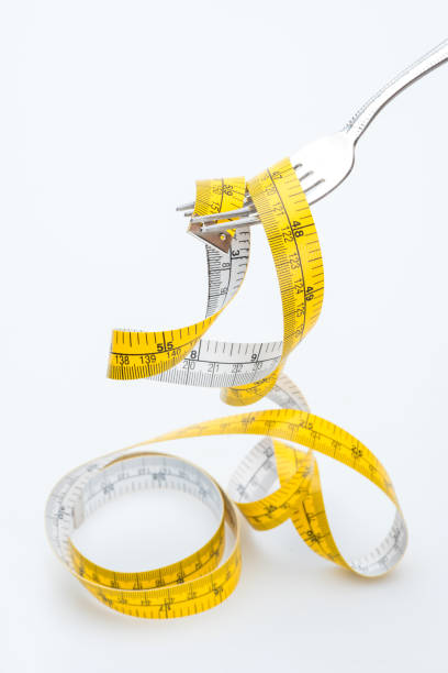 istock measuring tape on fork isolated on white, healthy living concept 682517576