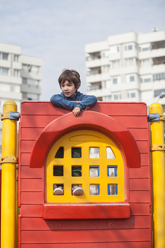 Little boy in casual clothes enjoying in playground in city.He has brown hair.Shot in day time with a full frame DSLR camera and tale photo lens.