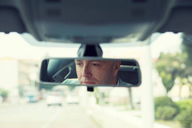 istock Closeup portrait serious young man driver reflection in rear view mirror isolated interior car windshield background 682547536
